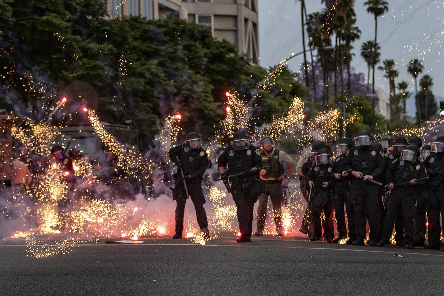 Fireworks thrown by a protester explode at the feet of Riverside police.