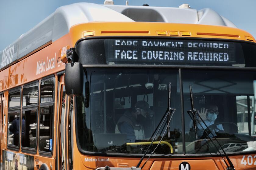 A Los Angeles Metro bus with an electronic display requiring a face mask is seen as the driver pulls out of a bus stop in Los Angeles on Tuesday, April 19, 2022. A federal judge's decision to strike down a national mask mandate was met with cheers on some airplanes but also concern about whether it's really time to end the order sparked by the COVID-19 pandemic. (AP Photo/Richard Vogel)