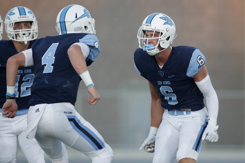 Corona del Mar High wide receiver John Humphreys (6) celebrates with quarterback Ethan Garbers (4) after the two connected for a touchdown reception against Downey during the first half in a season opener on Friday at Newport Harbor High.