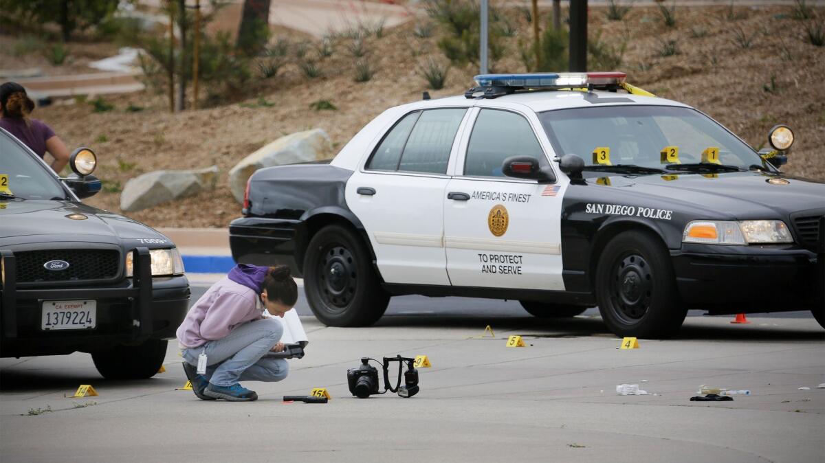 A member of the San Diego Police Department examines what appears to be a gun on the ground at the scene of a fatal police officer involved shooting of a 15-year-old boy in one of the parking lots in front of Torrey Pines High School, early Saturday morning.