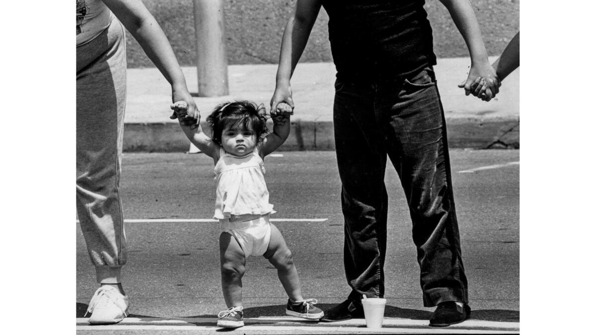May 25, 1986: Cynthia Gomez, 8 months, holds hands with her family in East Los Angeles during Hands Across America.