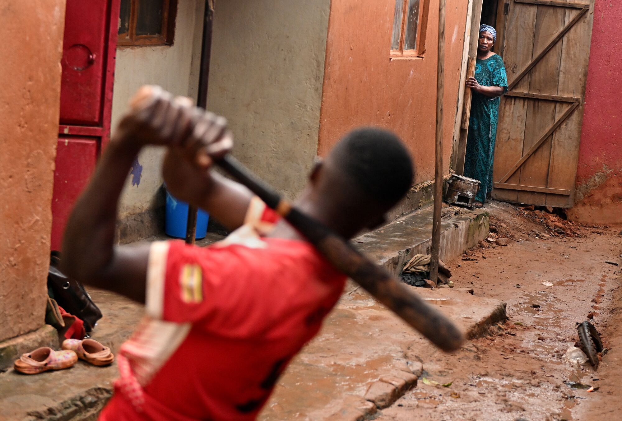 Dennis Kasumba ćwiczy swoją huśtawkę, gdy jego babcia Edith Natenza ogląda się na zewnątrz tamtejszego domu.