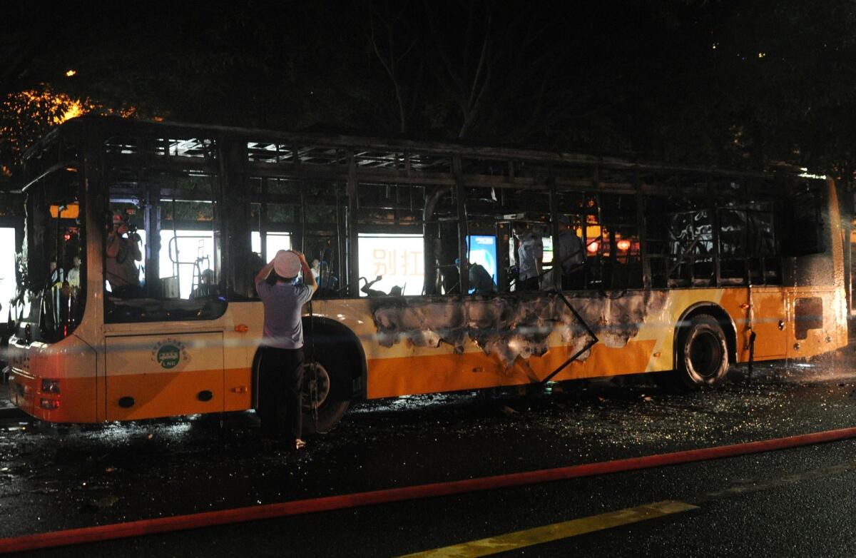 Investigators inspect the wreckage of a bus that was set on fire this week in Guangzhou, China.