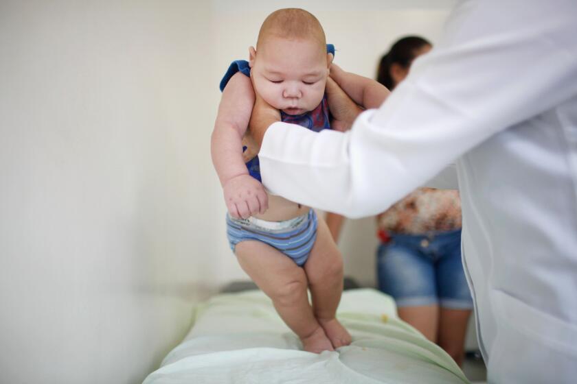 David Henrique Ferreira, 5 months, was born with microcephaly in Brazil. Here a doctor examines him in Recife.
