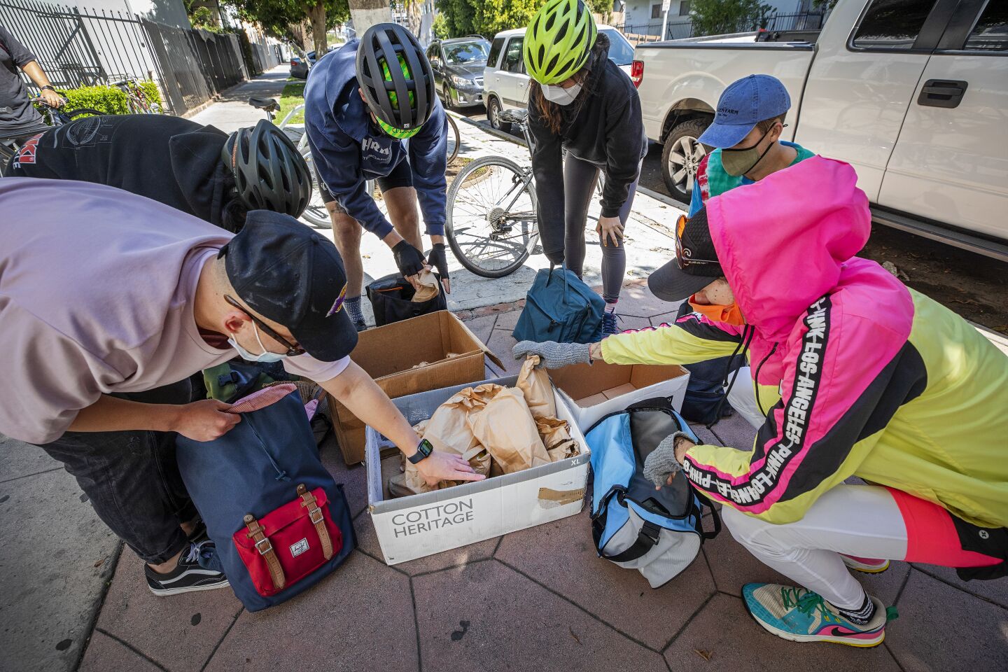 Bicycle Meals volunteers load up their backpacks with bags of food before heading out to deliver to the homeless around Koreatown.