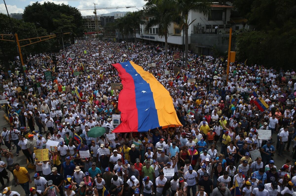 Anti-government protesters, some carrying a giant Venezuelan flag, march Sunday in Caracas, Venezuela.