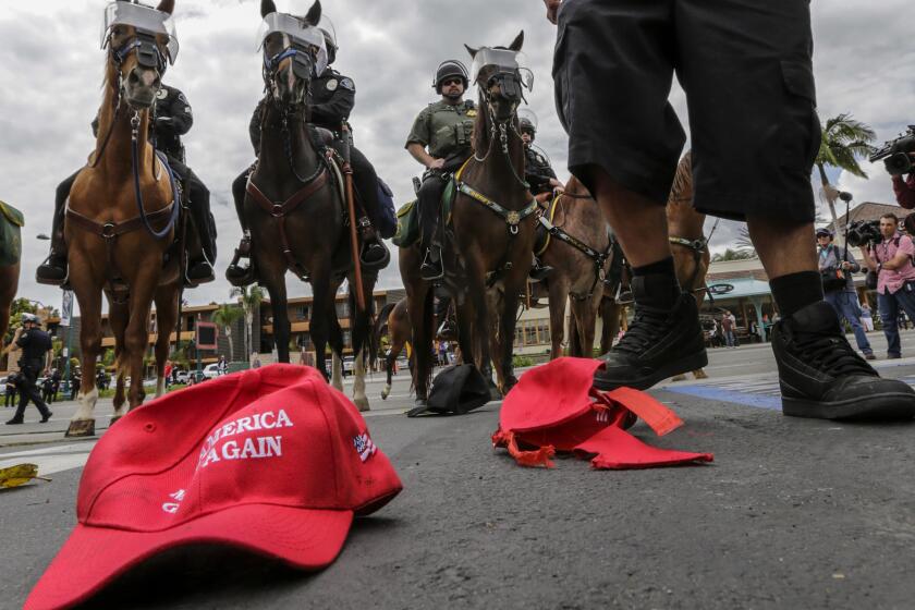 A protester stomps on Donald Trump "Make America Great Again" baseball caps on the ground behind the Anaheim Convention Center while a Trump campaign rally is underway in May.