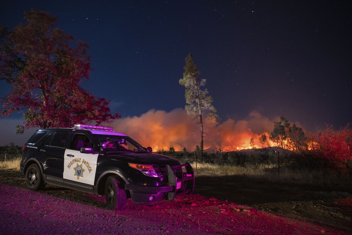 From a patrol vehicle, a CHP officer watches flames from the Zogg fire.