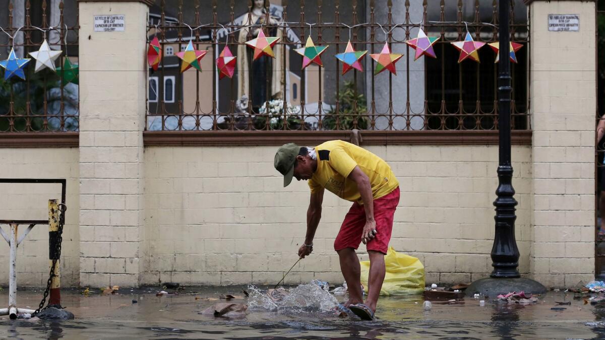 A man cleans trash deposited by flooding from Typhoon Nock-Ten in Quezon, Philippines, on Dec. 26.