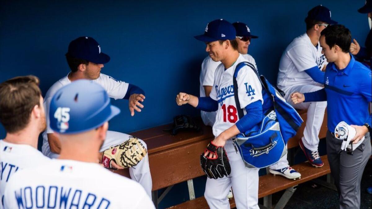 Dodgers pitcher Kenta Maeda (18) is greeted in the dugout by his teammates before a spring training game against the Colorado Rockies on Feb. 27.