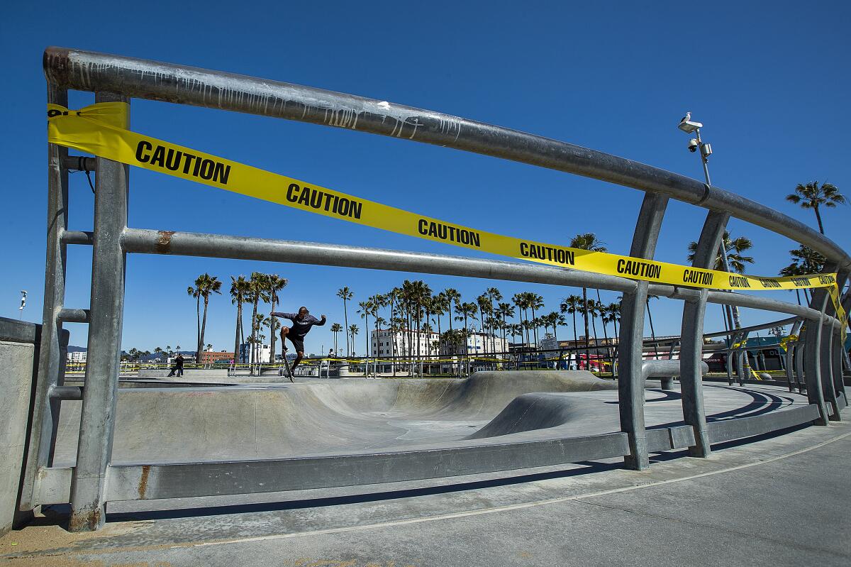 VENICE BEACH, CA-MARCH 27, 2020: A skateboarder ignores the yellow caution tape, placed around the skatepark at Venice Beach, to prevent the spread of the coronavirus. (Mel Melcon/Los Angeles Times)