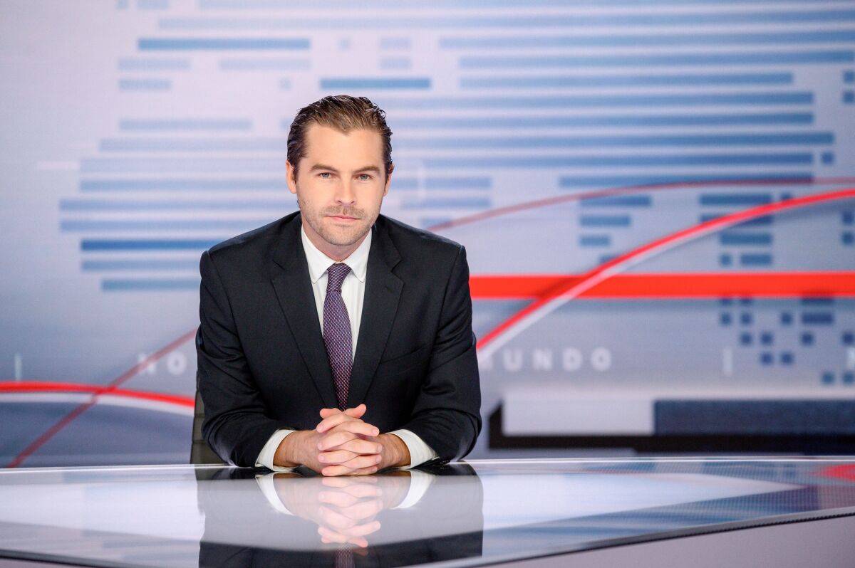 A photo of a man in a suit on the set of a TV news show