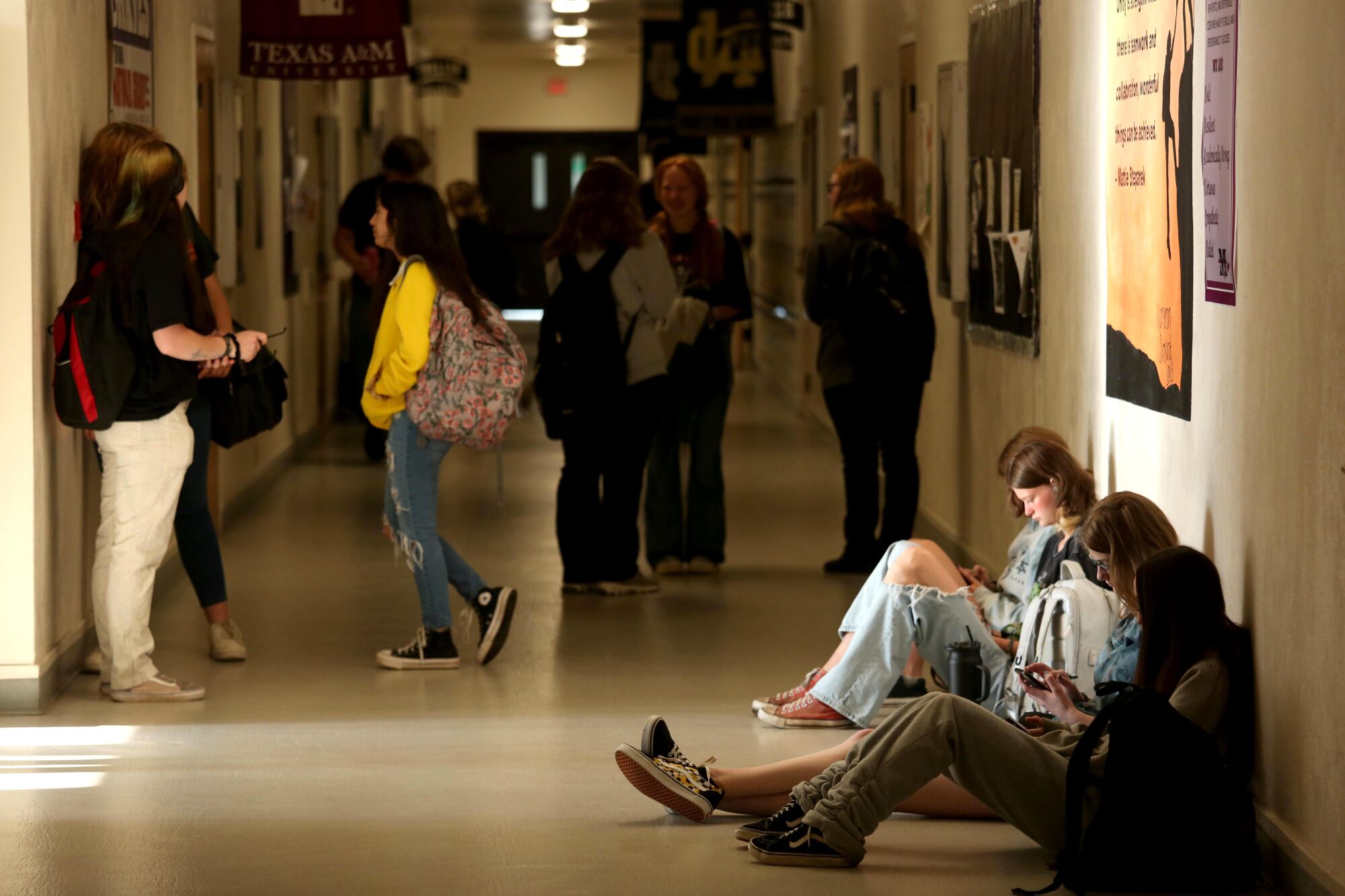 Students sit and stand in a hallway waiting for classes to begin.