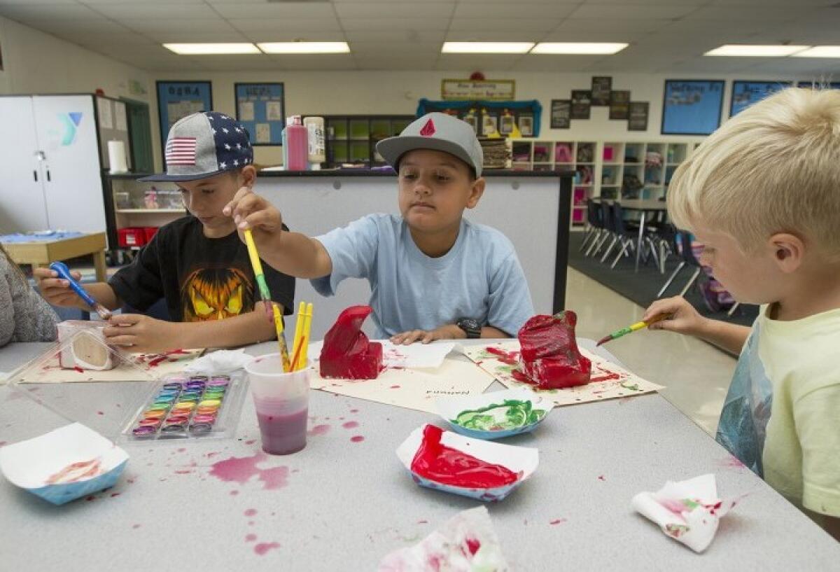 Students decorate art pieces during a YMCA of Orange County summer learning program at Peterson Elementary School in Huntington Beach in 2017. Some parents are worried the campus will be closed amid anticipated budget cuts.
