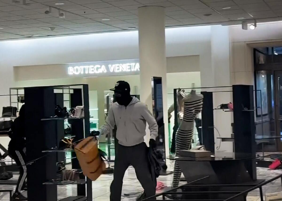 A masked man holding bags in a department store.