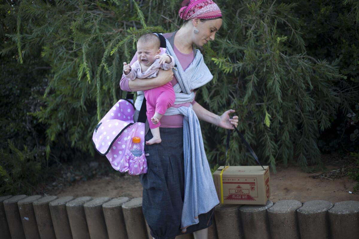 An Israeli woman carries a boxed gas mask while holding a child outside a government distribution center in Tel Aviv.