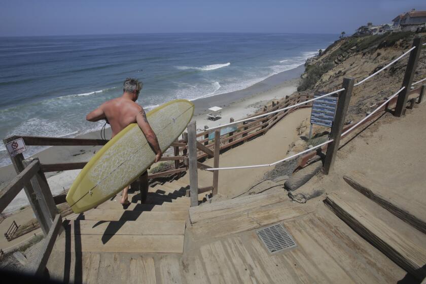 A surfer uses the stairs down to Beacon's Beach in Encinitas after the trail reopened.