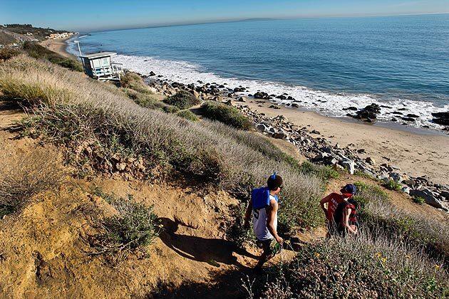After parking along Pacific Coast Highway for free, Collins Holliday, left, and Raffi Damadyan, both of Reseda, make their way down a dirt path to play football at Dan Blocker County Beach in Malibu. Although it's used quite a bit by the public, there are no amenities or improvements like permanent restrooms, a parking lot or steps. For decades, Dan Blocker beach, a one-mile stretch of Malibu coastline, has sat with no improvements offered by the Los Angeles County Department of Beaches and Harbors.