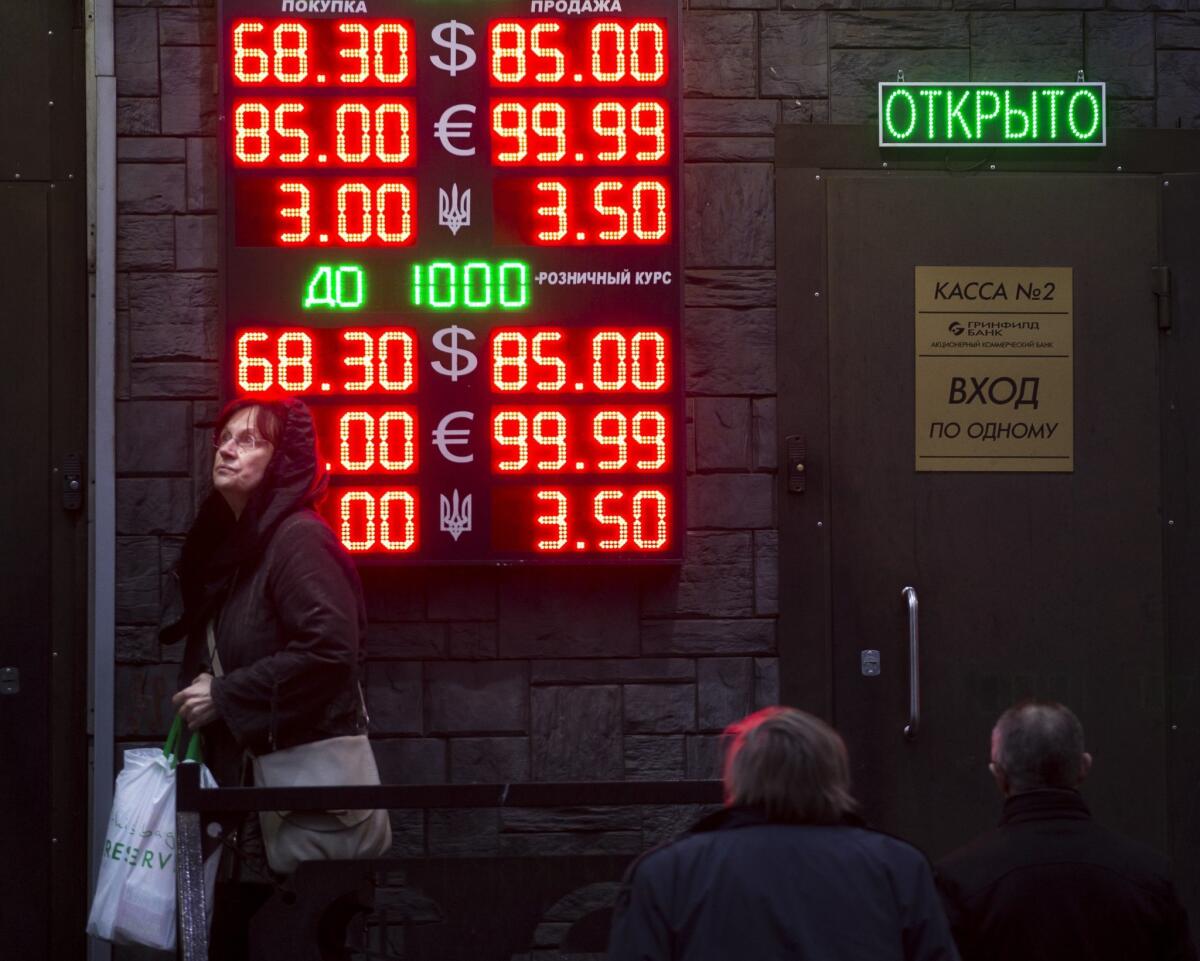 People wait to exchange currency near a sign advertising exchange rates at an exchange office in Moscow on Dec. 16.