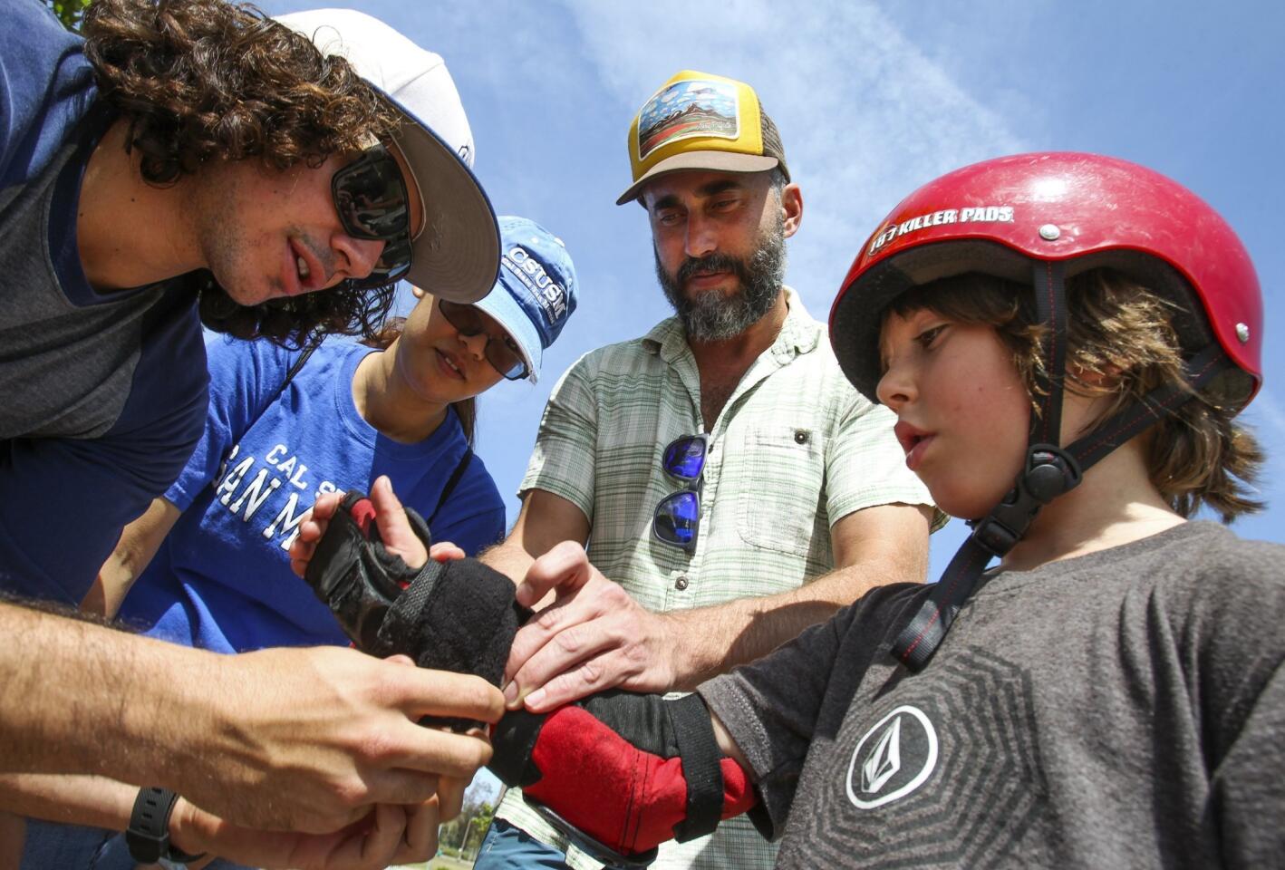 Cal State University San Marcos intern Moses Wosk, 24, left, puts a protective cover over a wrist device, that records heart rate, length of time skating and distance, on Judah Mann, 6.