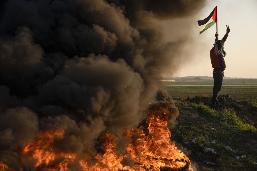 Palestinians burn tires and wave the national flag during a protest against Israeli military raid in the West Bank city of Jenin, along the border fence with Israel, in east of Gaza City, Thursday, Jan. 26, 2023. During the raid in the West Bank town of Jenin, Israeli forces killed at least nine Palestinians, including a 60-year-old woman, and wounded several others, Palestinian health officials said, in one of the deadliest days of fighting in years. The Israeli military said it was conducting an operation to arrest militants when a gun battle erupted. (AP Photo/Fatima Shbair)
