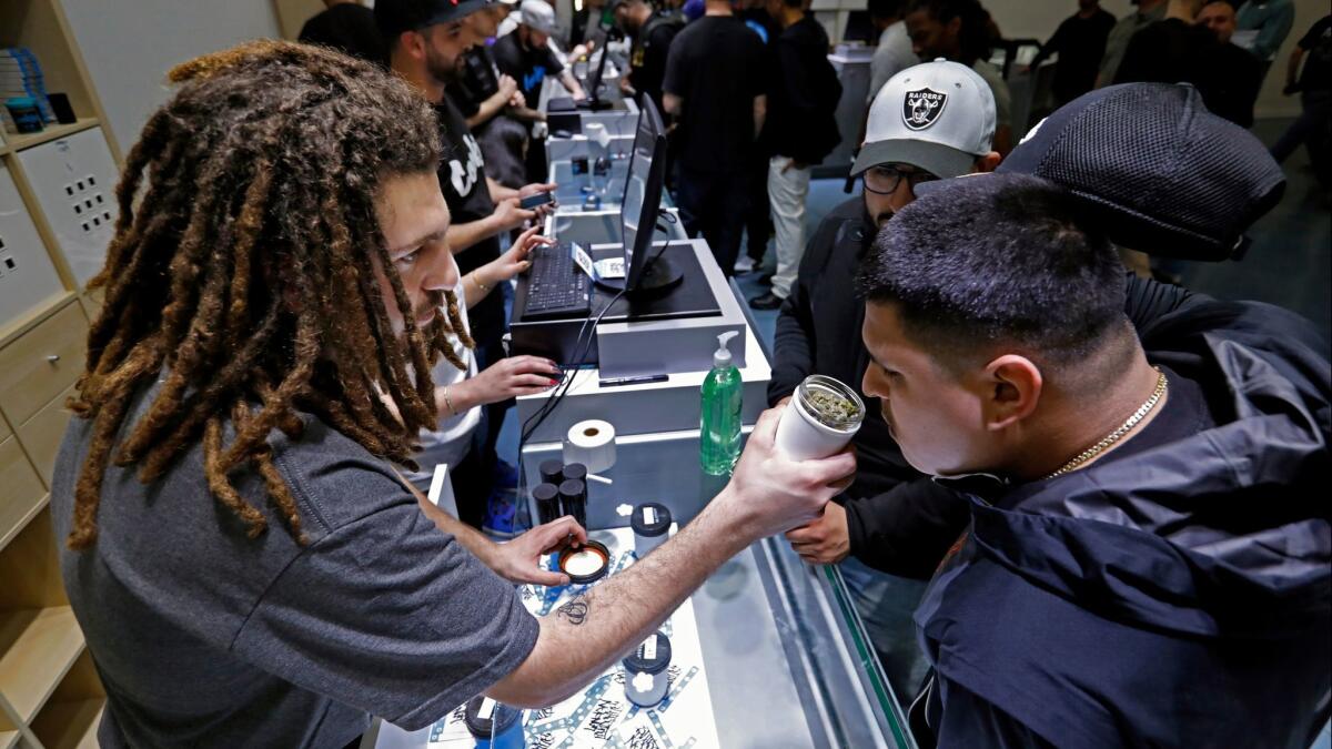 Shant Damirdjian, left, assists customers at the grand opening of Cookies Los Angeles, which sells recreational marijuana under Proposition 64.