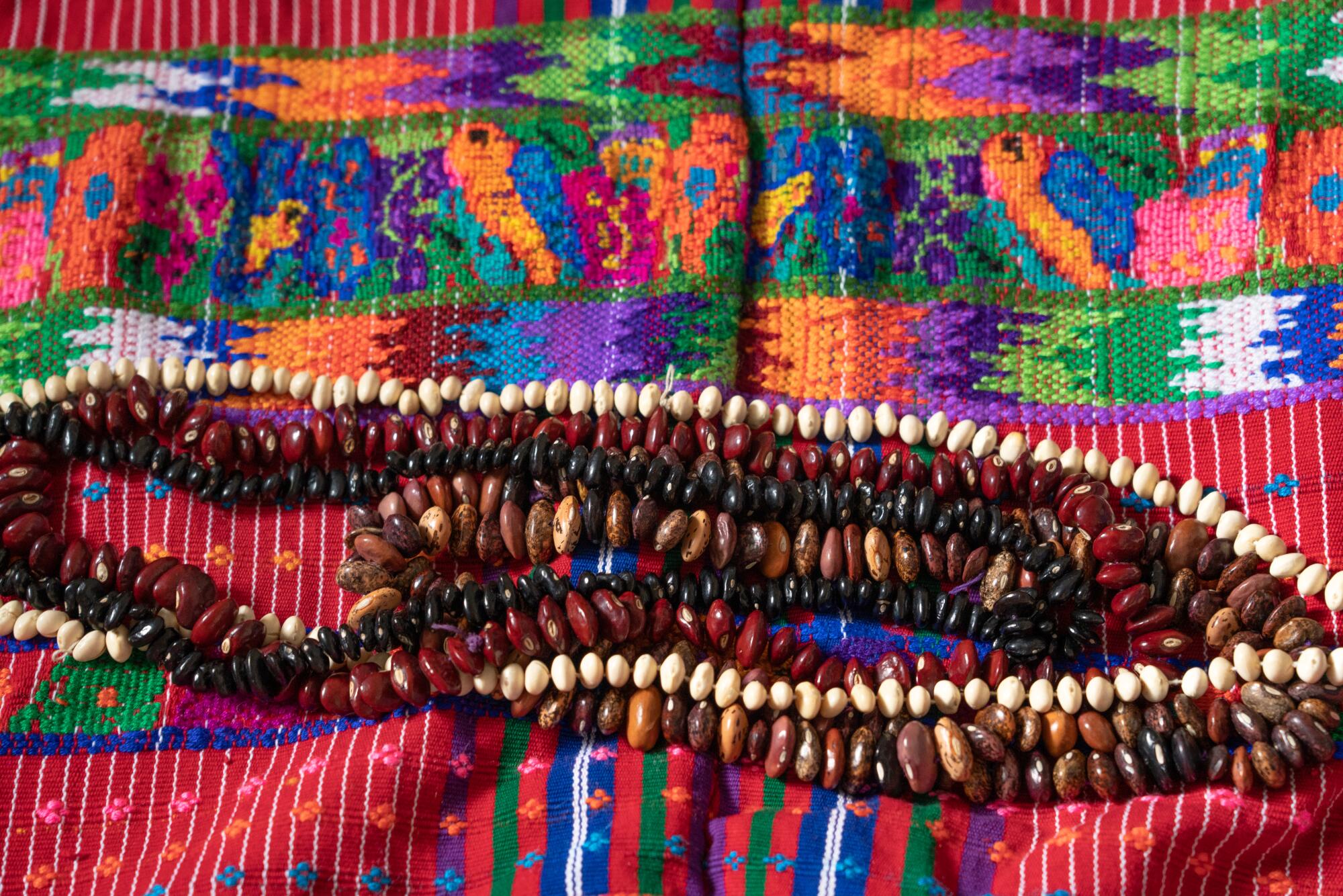 Necklaces made from beans on a colorful woven cloth.