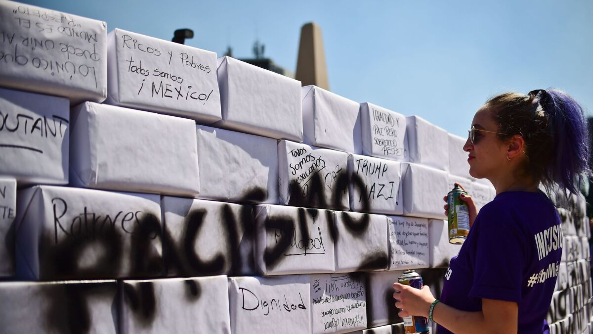 An activist writes the word "racism" on a mock border wall during an anti-Trump march in Mexico City on Feb. 12.