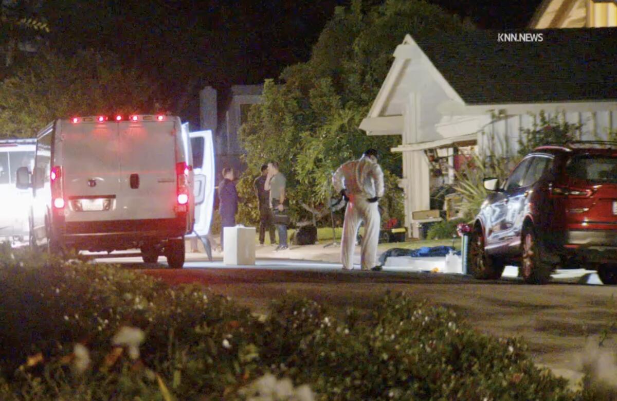 Emergency vehicles with lights on outside a University Park home where investigators gather in the yard.