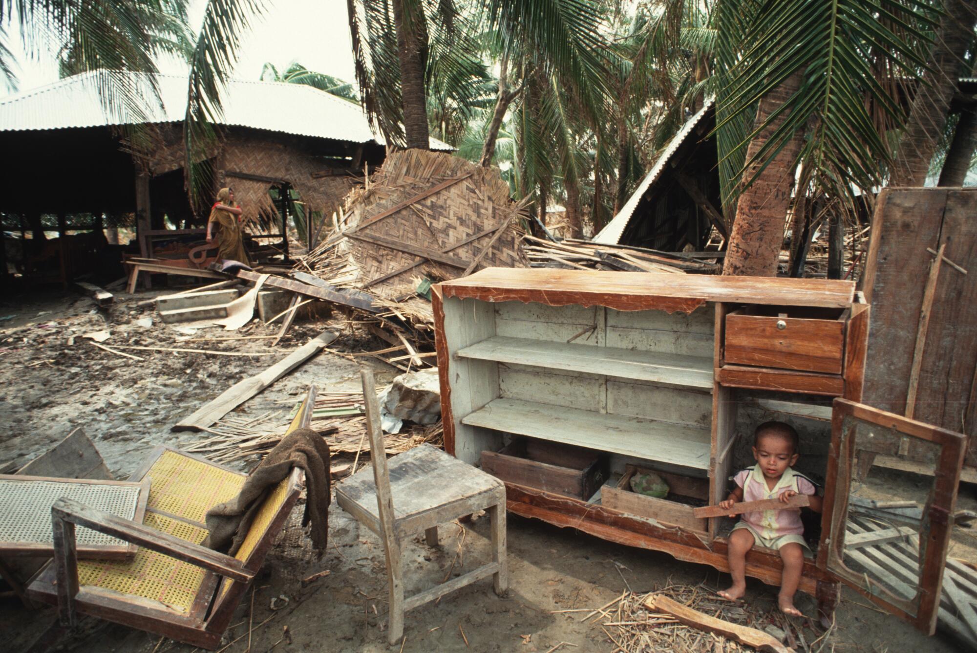 A child sits among the wreckage of a village devastated by the 1991 cyclone in Bangladesh.