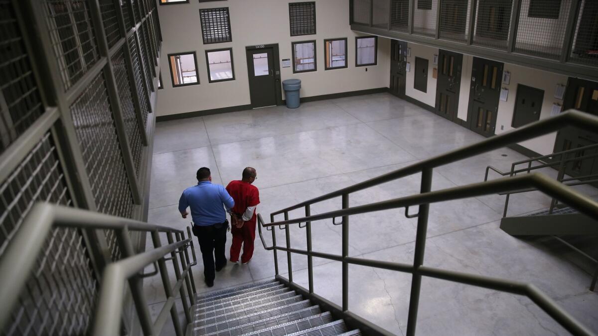 A guard escorts an immigrant detainee from his 'segregation cell' back into the general population at the Adelanto Detention Facility in Adelanto, California.