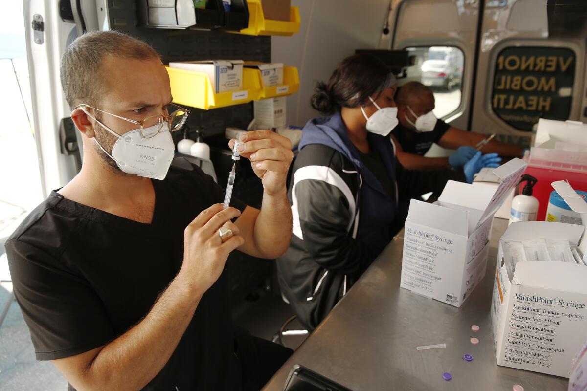 Healthcare workers prepare doses of the COVID-19 vaccine.