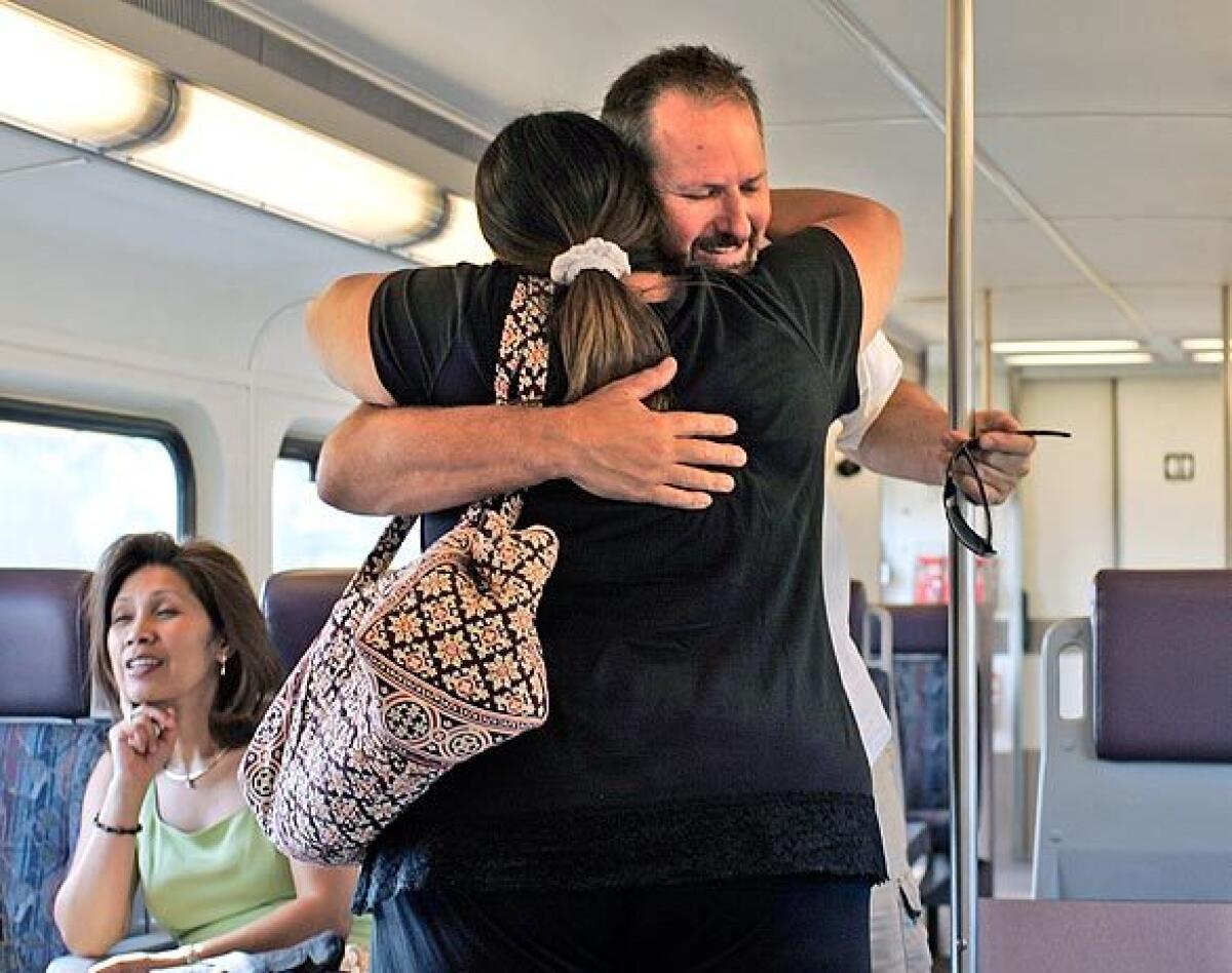 Metrolink passengers Brad Runkle of Simi Valley and Lexi Bagheri of West Hills hug aboard train 111 as it resumes evening service. It was the first time they had seen each other since the day before the deadly Metrolink crash.