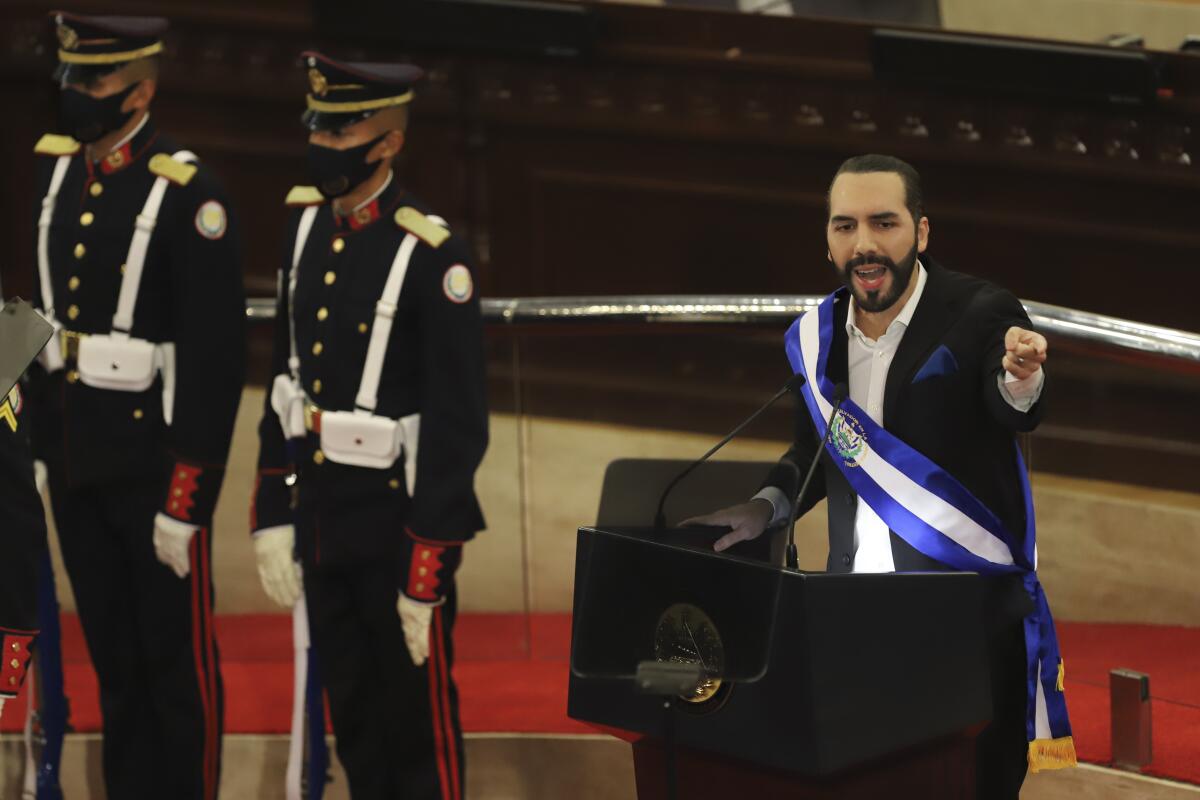 El Salvador President Nayib Bukele gestures from behind a lectern. 