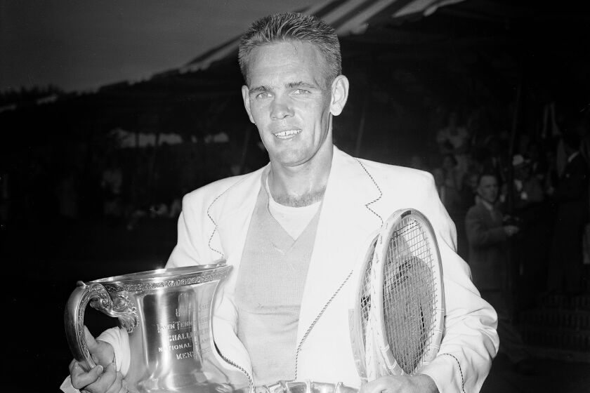 Jack Kramer stands at the West Side Tennis Club in Forest Hills, New York, with the trophies.