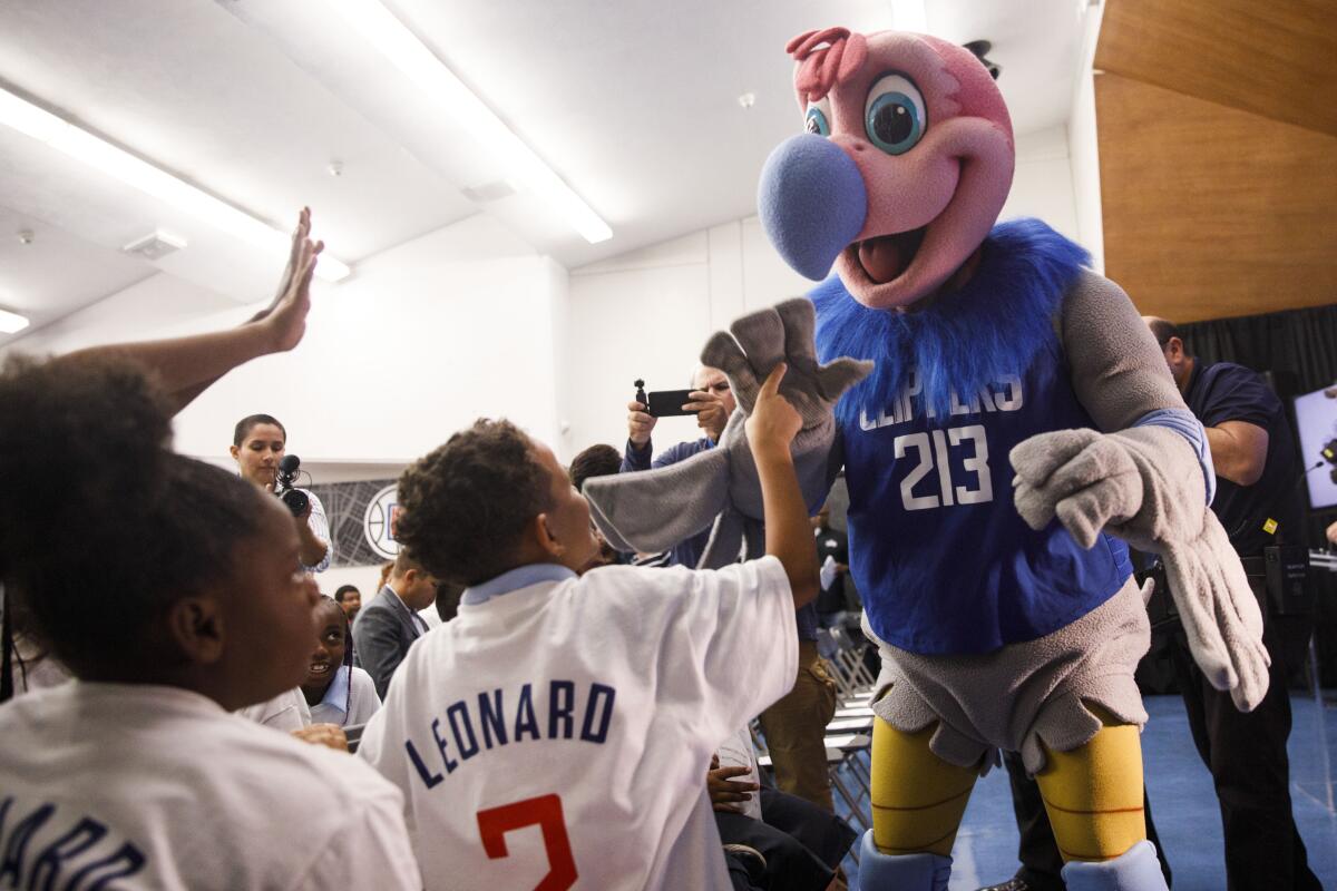 Clippers mascot "Chuck" high fives students before Kawhi Leonard gives backpacks away to students at One Hundred Seventh Street Elementary School on Tuesday in the Watts neighborhood of Los Angeles.