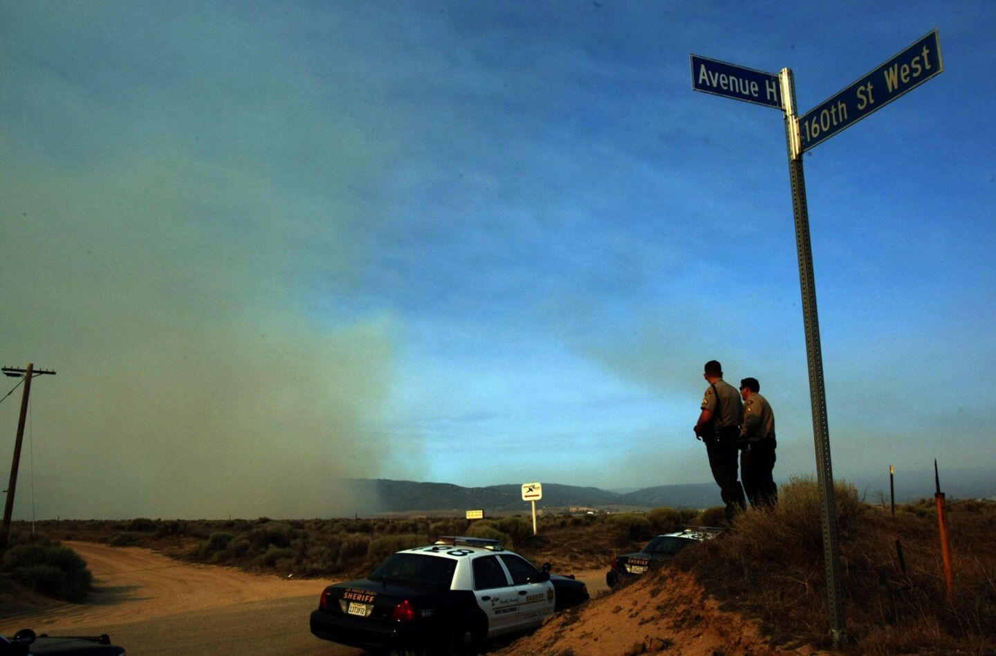 Los Angeles County sheriff's deputies keep an eye on a plume of smoke from the Powerhouse fire along 160th Street West in Lake Hughes.