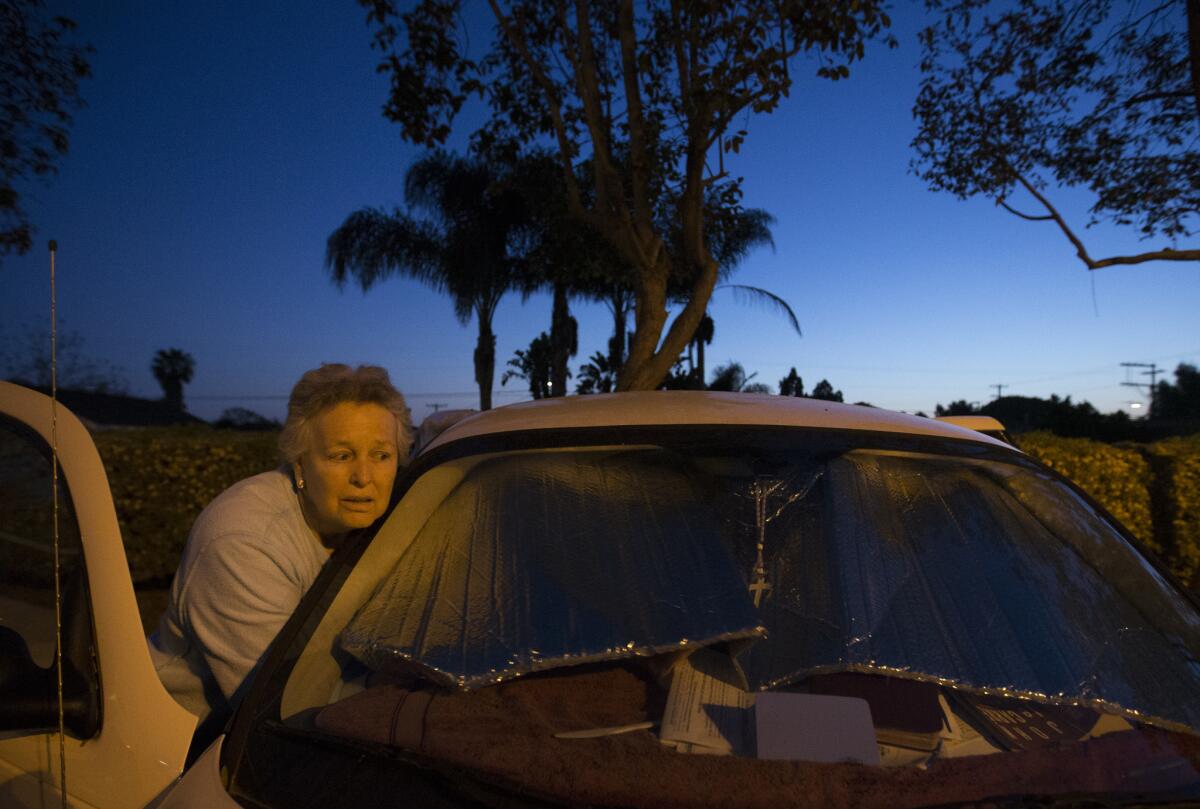 Russell blocks out the windows and rearranges her belongings to make room for sleeping in her car at the Carlsbad Senior Center.