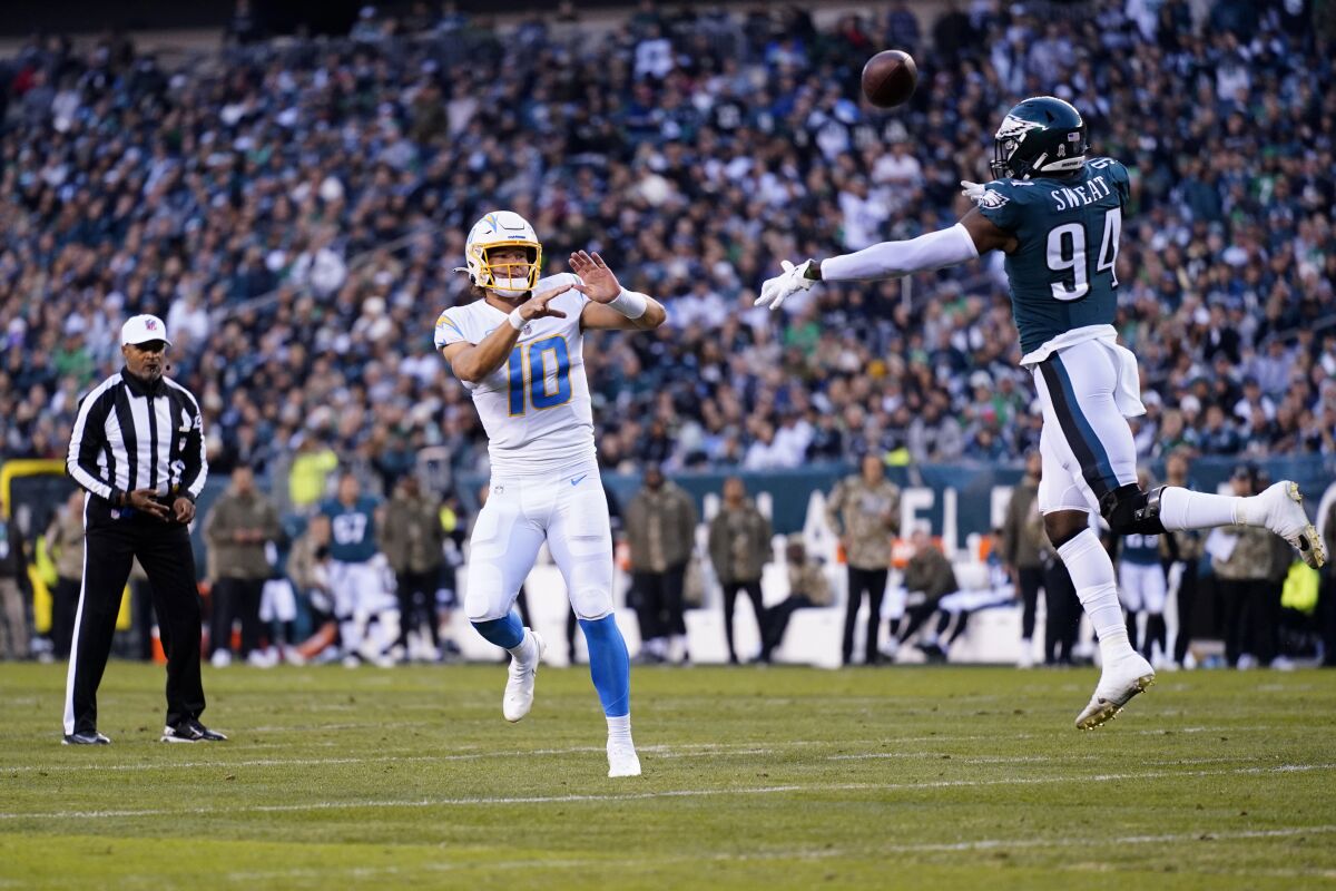 Los Angeles Chargers quarterback Justin Herbert (10) throws a touchdown pass in front of Philadelphia Eagles defensive end Josh Sweat (94) to Los Angeles Chargers tight end Stephen Anderson during the first half of an NFL football game Sunday, Nov. 7, 2021, in Philadelphia. (AP Photo/Matt Rourke)