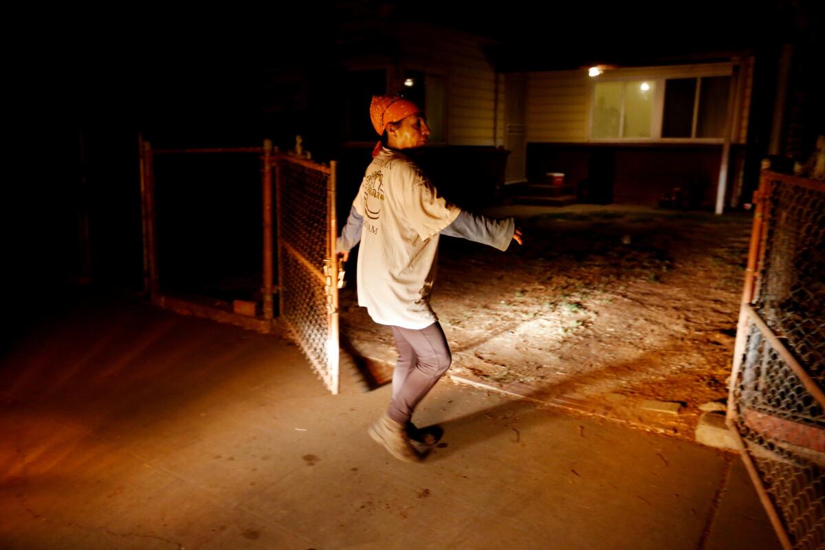 Lourdes Cardenas, 53, locks the gate to her home before driving to a gas station to meet other farmworkers to pick grapes in Fresno. (Gary Coronado / Los Angeles Times)