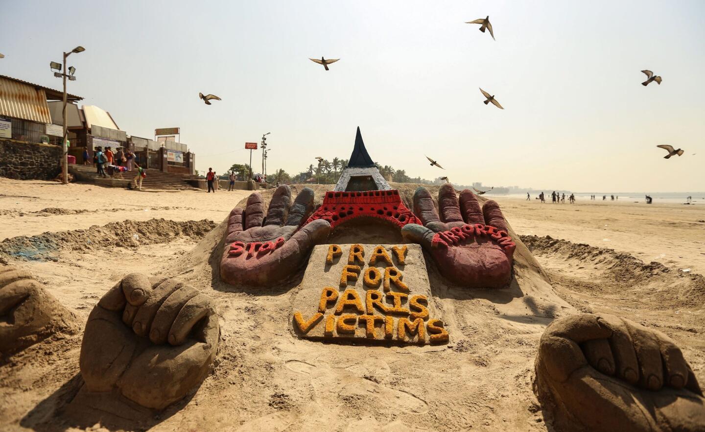 Pigeons fly over a sand sculpture paying tribute to the victims of the Paris terrorist attacks in Mumbai, India, on Nov. 20, 2015.