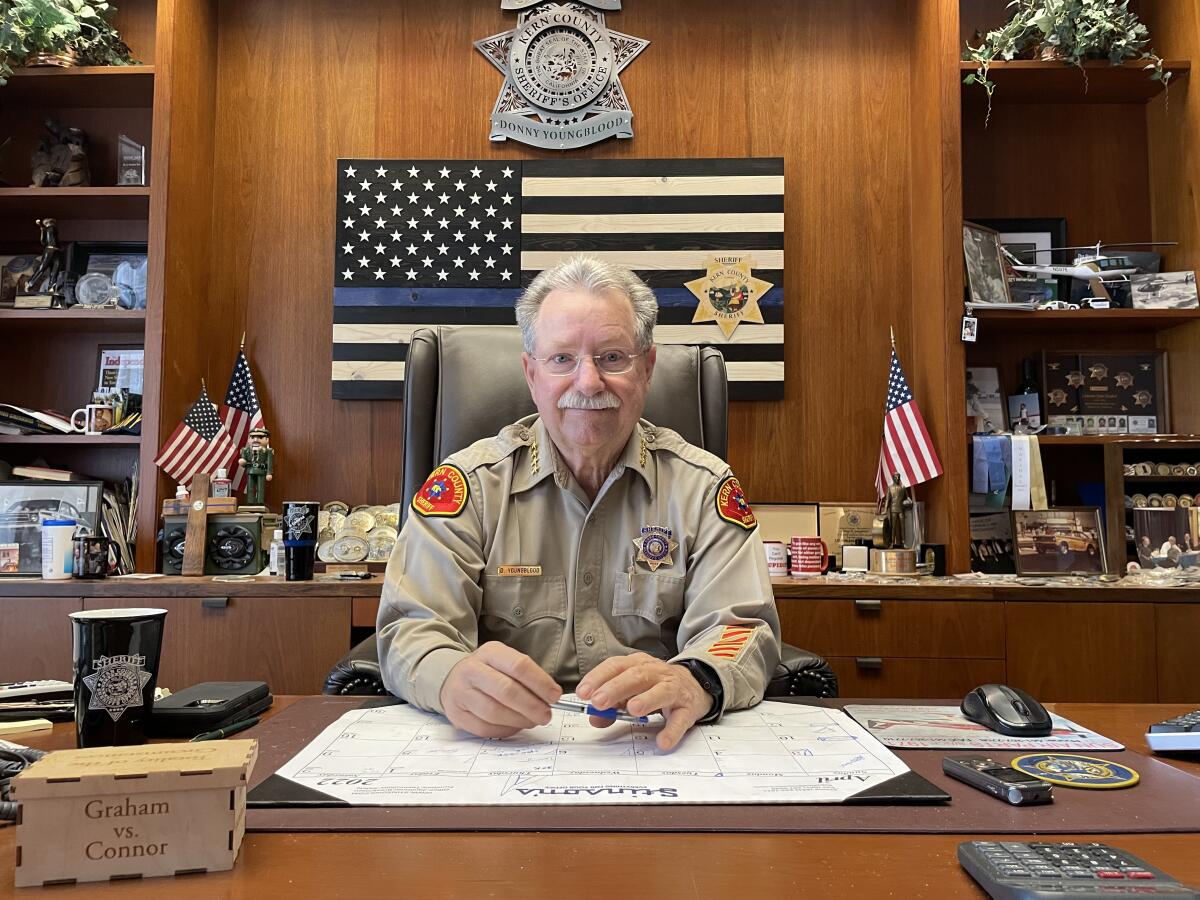 A man in a sheriff's uniform sits at a desk