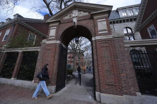 FILE - Pedestrians walk through the gates of Harvard Yard at Harvard University, Wed