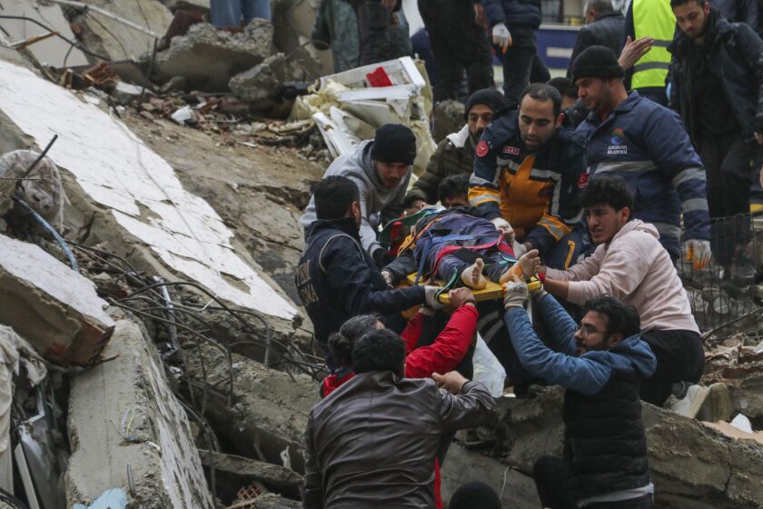 People and emergency teams rescue a person on a stretcher from a collapsed building in Adana, Turkey, Monday, Feb. 6, 2023. A powerful quake has knocked down multiple buildings in southeast Turkey and Syria and many casualties are feared. (IHA agency via AP)