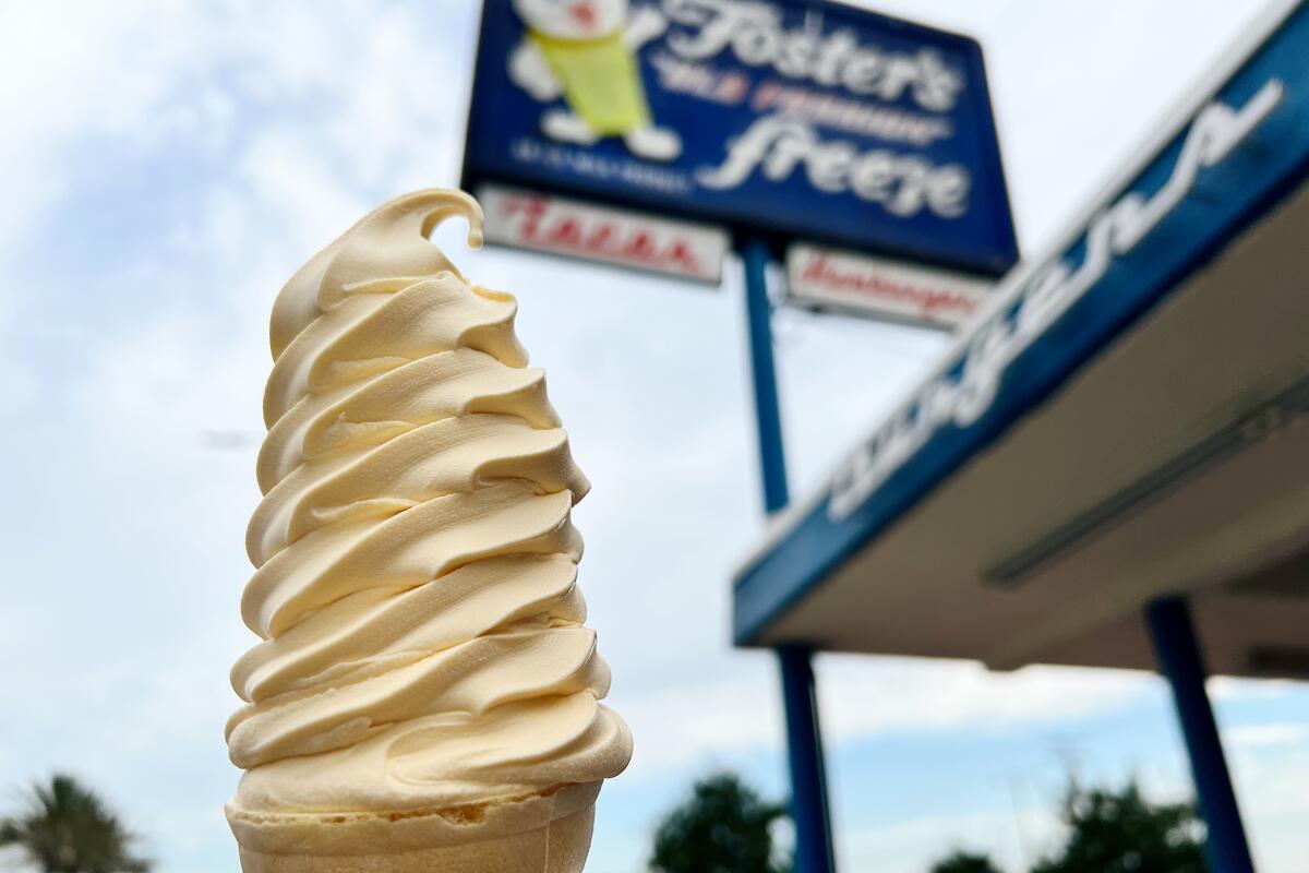 A cone of soft serve ice cream held up outside the original Fosters Freeze in Inglewood.