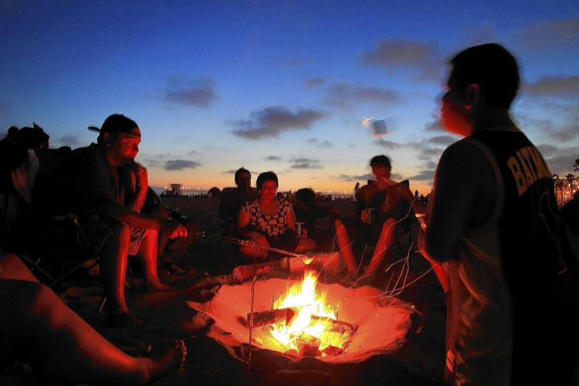 Fourth of July revelers roast marshmallows around a fire pit in Huntington Beach. An Assembly bill aiming to protect fire rings in Southern California was held back in the state Senate Appropriations Committee and will not be heard again this year.