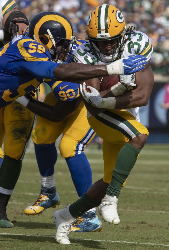Rams' Cory Littleton, left, stops Green Bay Packers' Aaron Jones on a first quarter run at the Coliseum on Sunday.