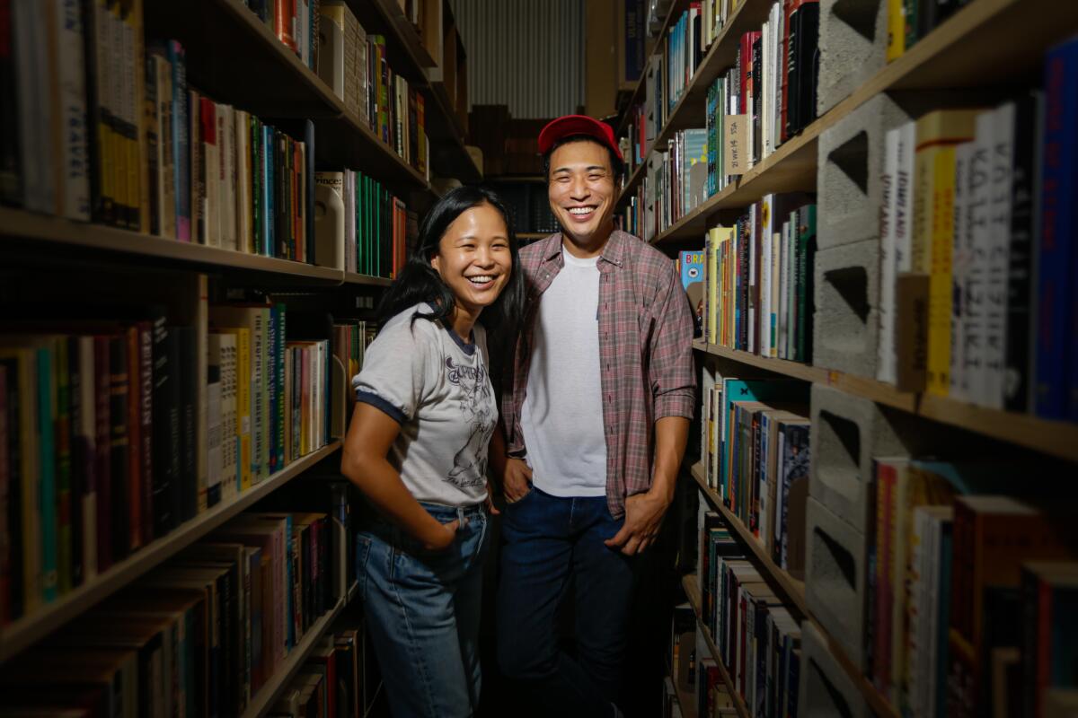 Jenny Yang and Chris Capizzi, co-owners of A Good Used Book, stand in between bookshelves