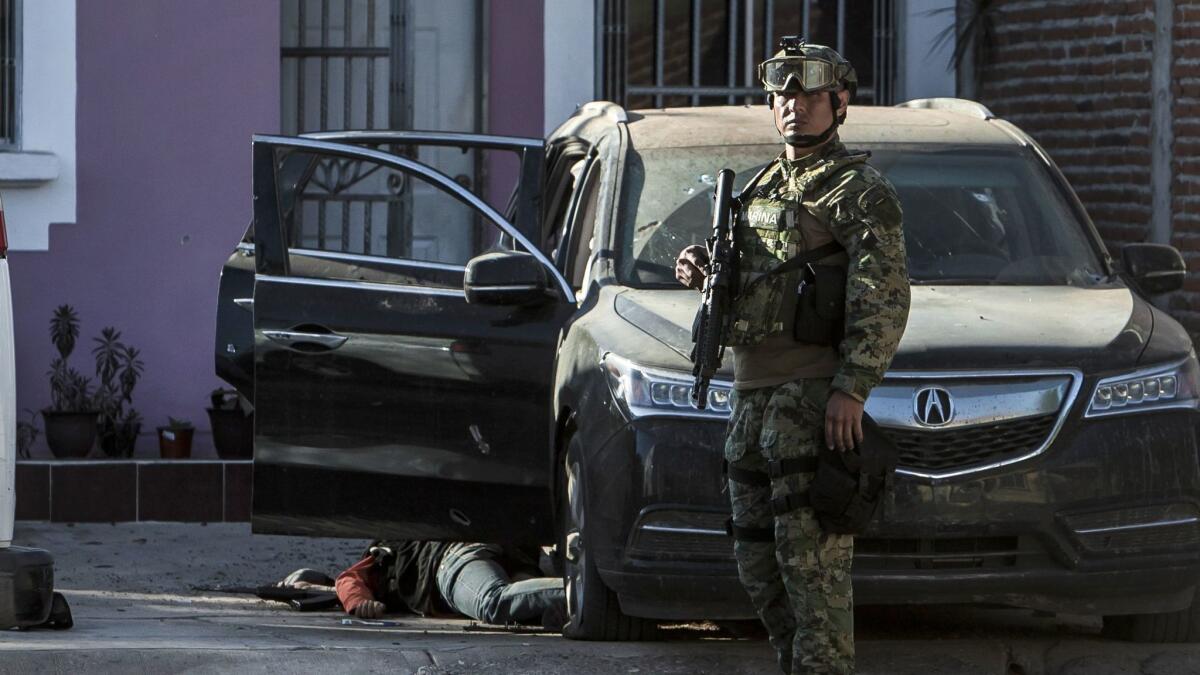 A Mexican marine stands by the body of a gunman after shots were exchanged in the city of Culiacan on Feb. 7. The Sinaloa state prosecutor's office said heavily armed men attacked the marines, leaving one of them dead.