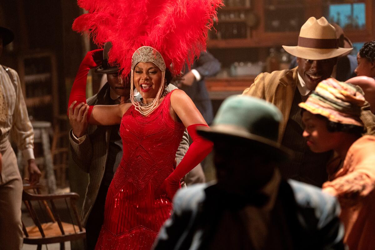 A woman in a bold red dress sings in a juke joint.
